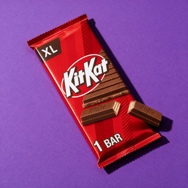 Chocolate bar wrapper on saturated purple poster backdrop with hard shadow — AI packaged food photography