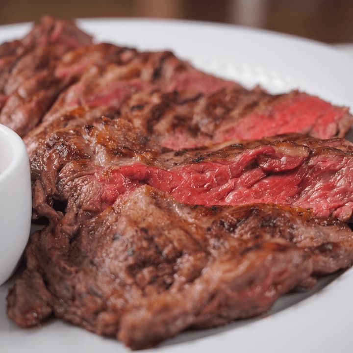Close view of sliced grilled steak on a white plate — steakhouse food photography