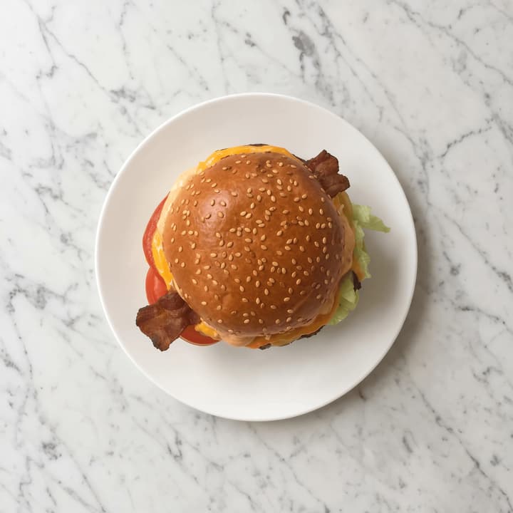 Single classic cheeseburger overhead marble top down sesame bun — iconic burger FAQ sidebar photography
