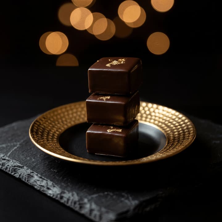Stack of square chocolate pralines edible gold leaf — iconic chocolatier photography FAQ sidebar