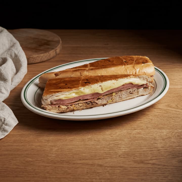 Cuban sandwich cubano cross section ham pork Swiss pickle macro board — iconic cubano FAQ sidebar photography
