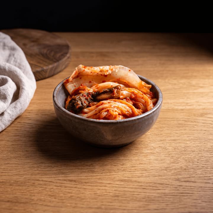 Napa cabbage kimchi baechu fermented red gochugaru glossy ceramic dish macro — kimchi FAQ sidebar photography