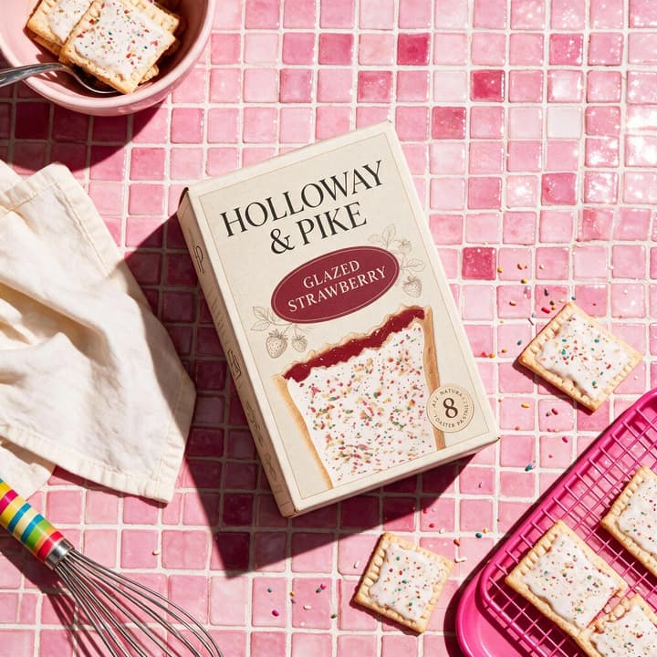 Toaster pastry box on glossy pink mosaic tile with pastries — playful packaged food photography by FoodShot AI