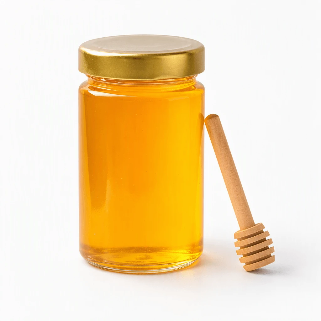 Single unlabelled hexagonal glass jar of golden honey with a wooden dipper resting against it on a seamless pure white background