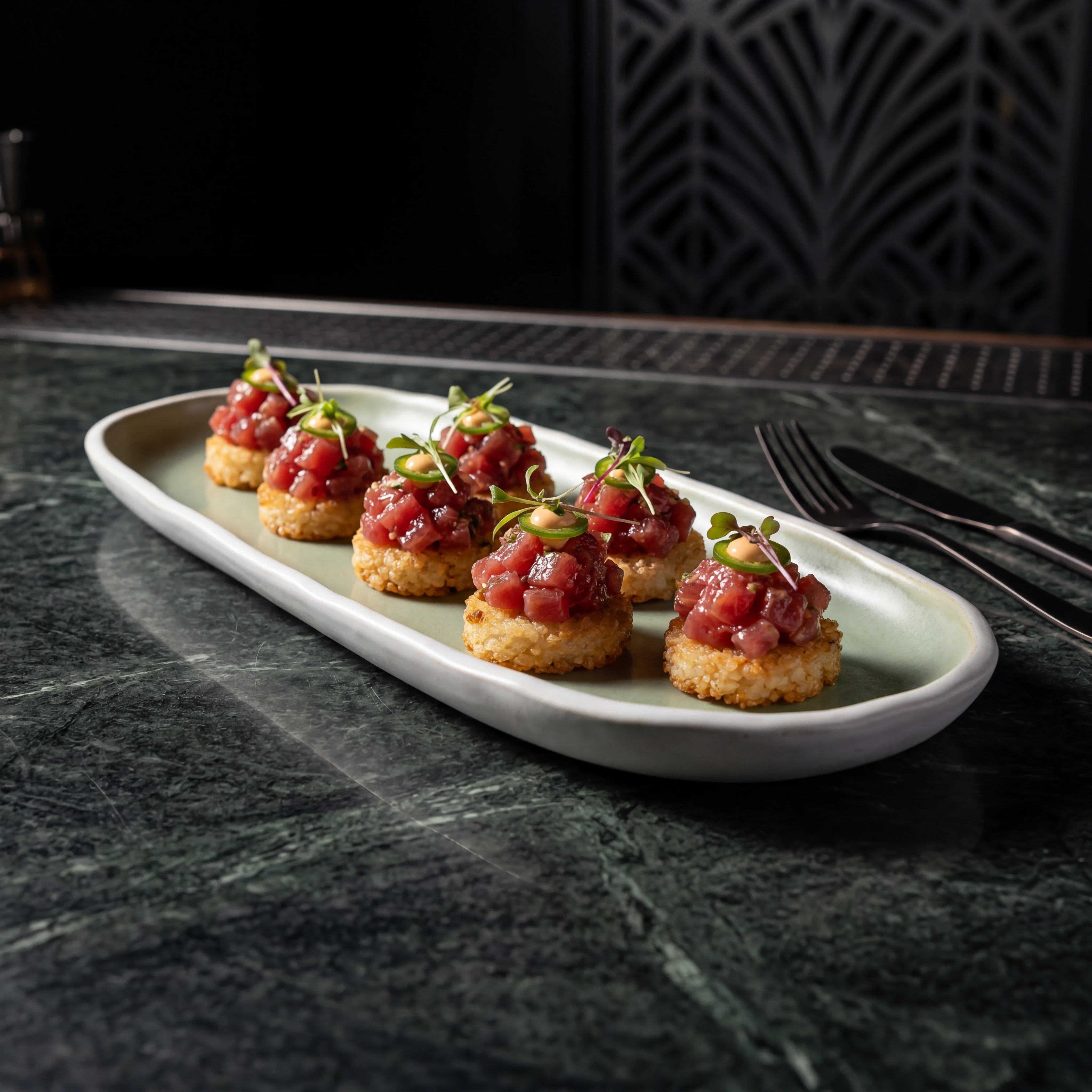 Tuna tartare on crispy rice — dark marble bar surface, premium cocktail bar food photography