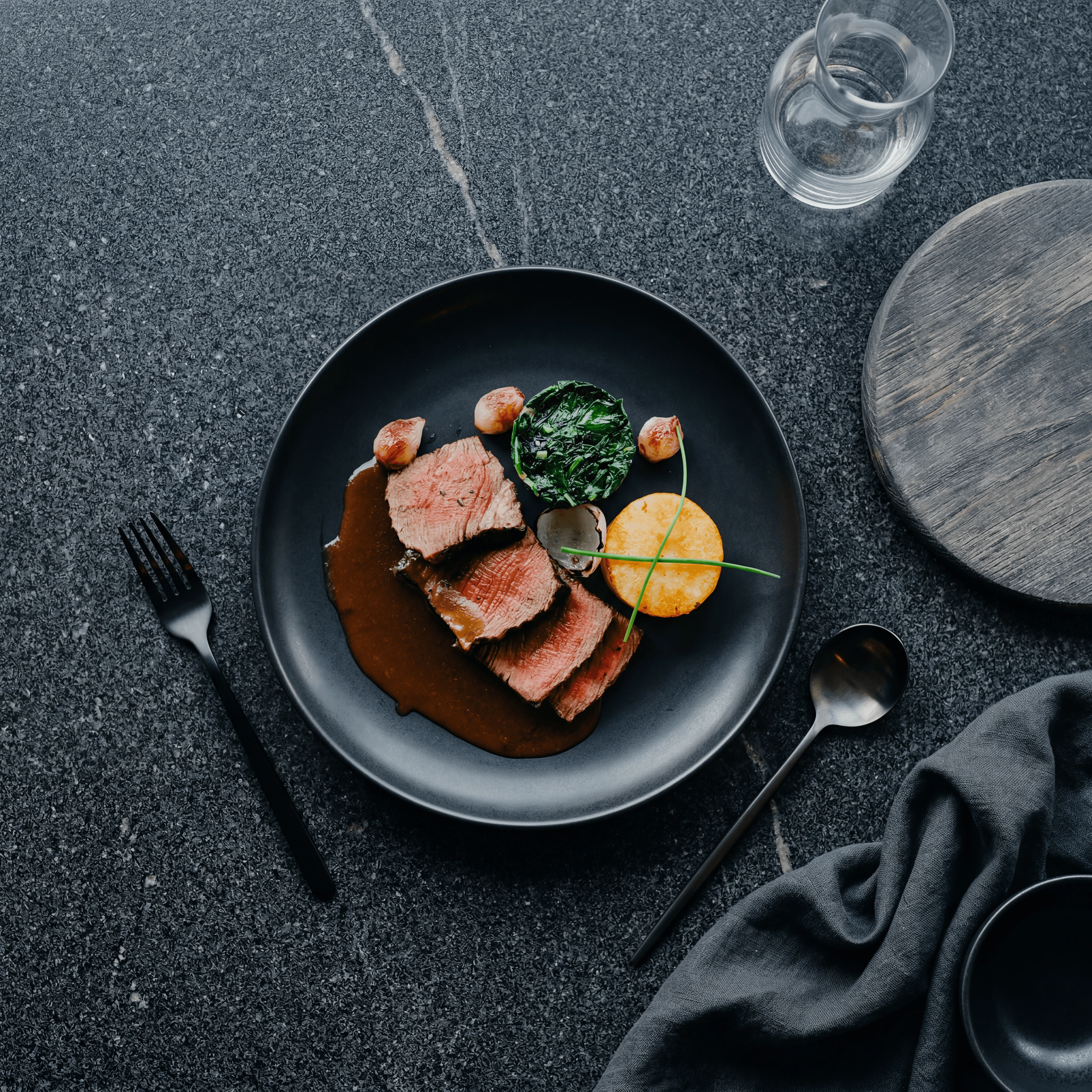 Makro-tværsnit af post-oak-røget brisket-skive med peberbark, koralfarvet røgring og marmoreret indre på mørkt skifer — redaktionel BBQ-fotografering