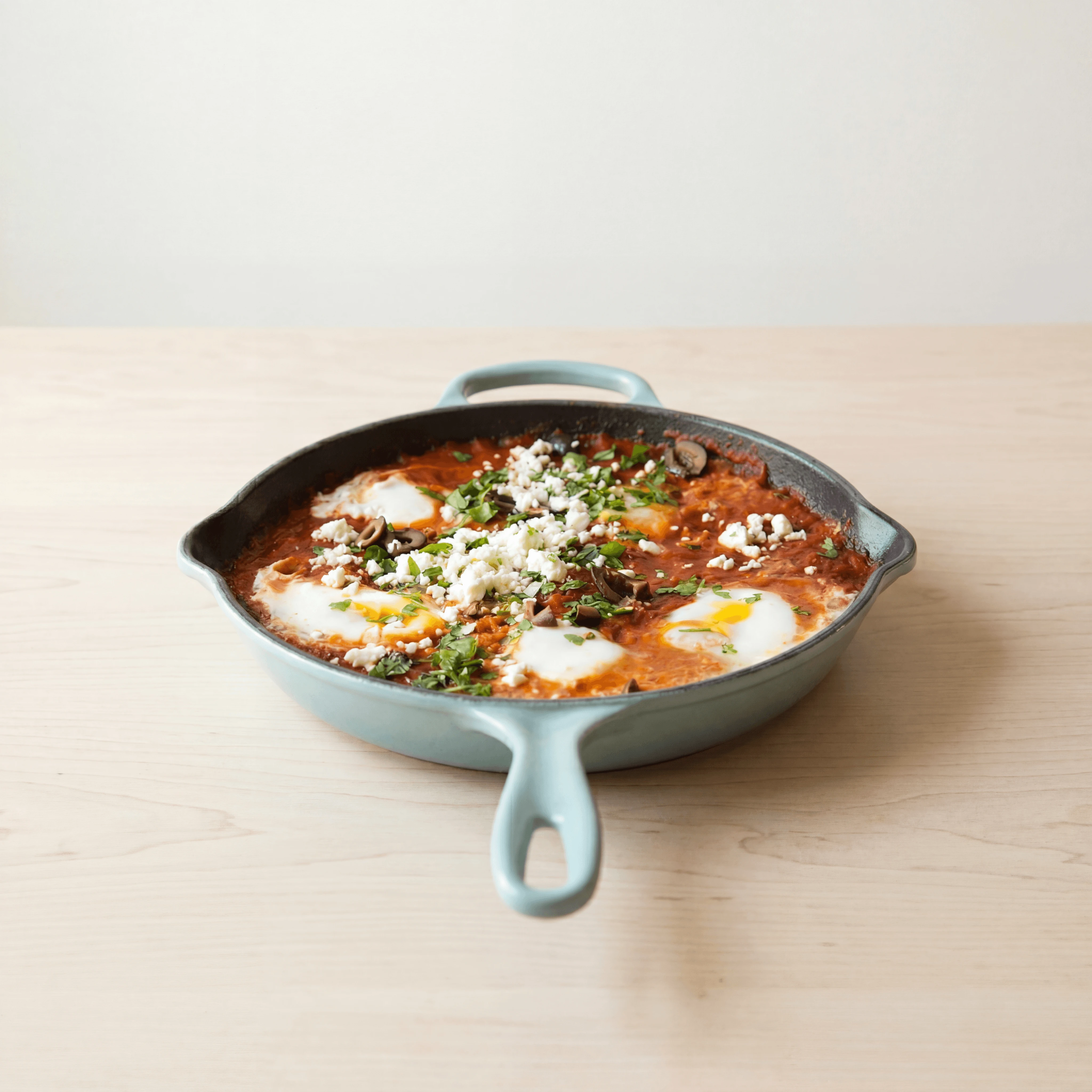 Shakshuka cast iron skillet poached eggs tomato sauce parsley — shakshuka hero photography
