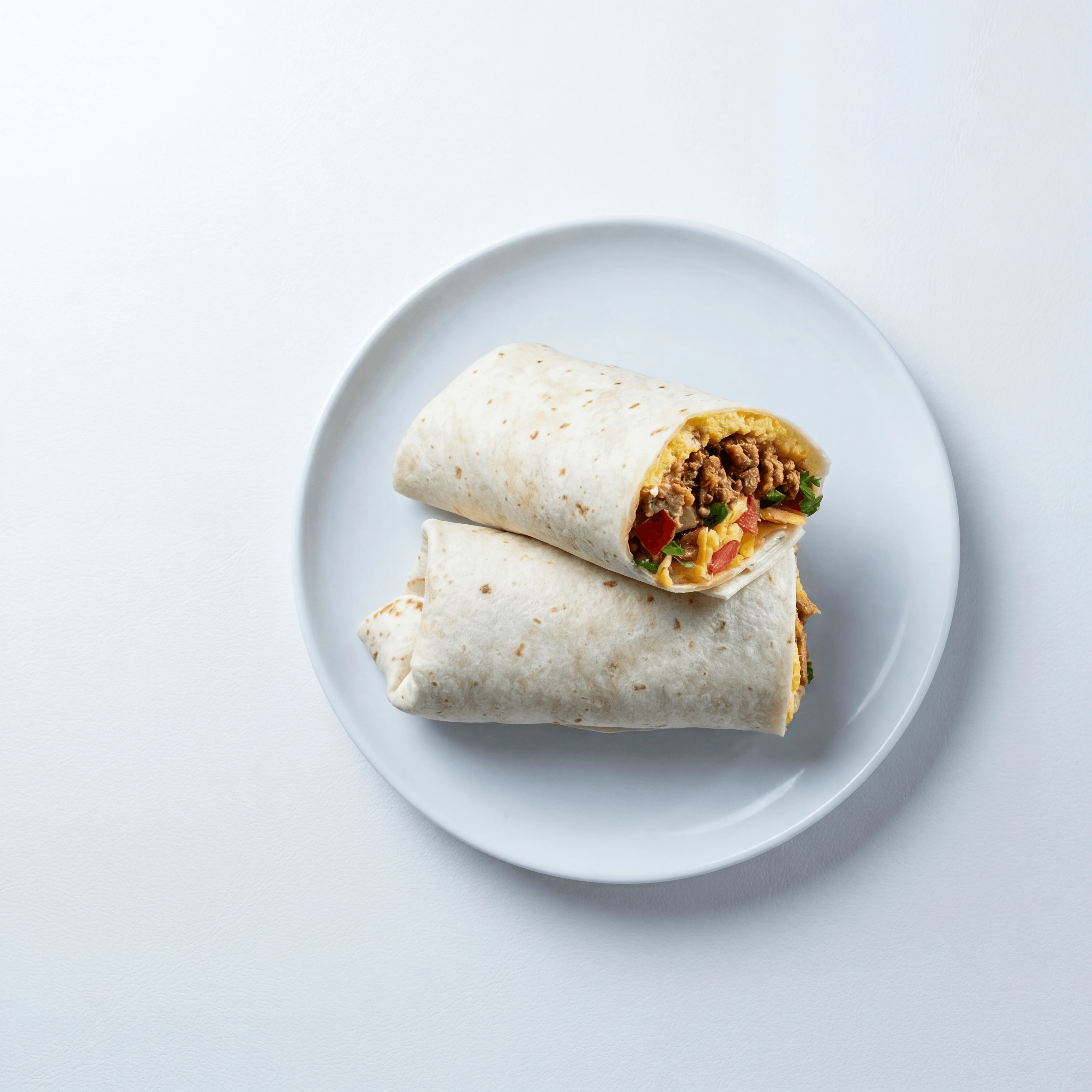 Breakfast burrito eggs chorizo cheese salsa plated white — breakfast burrito hero photography