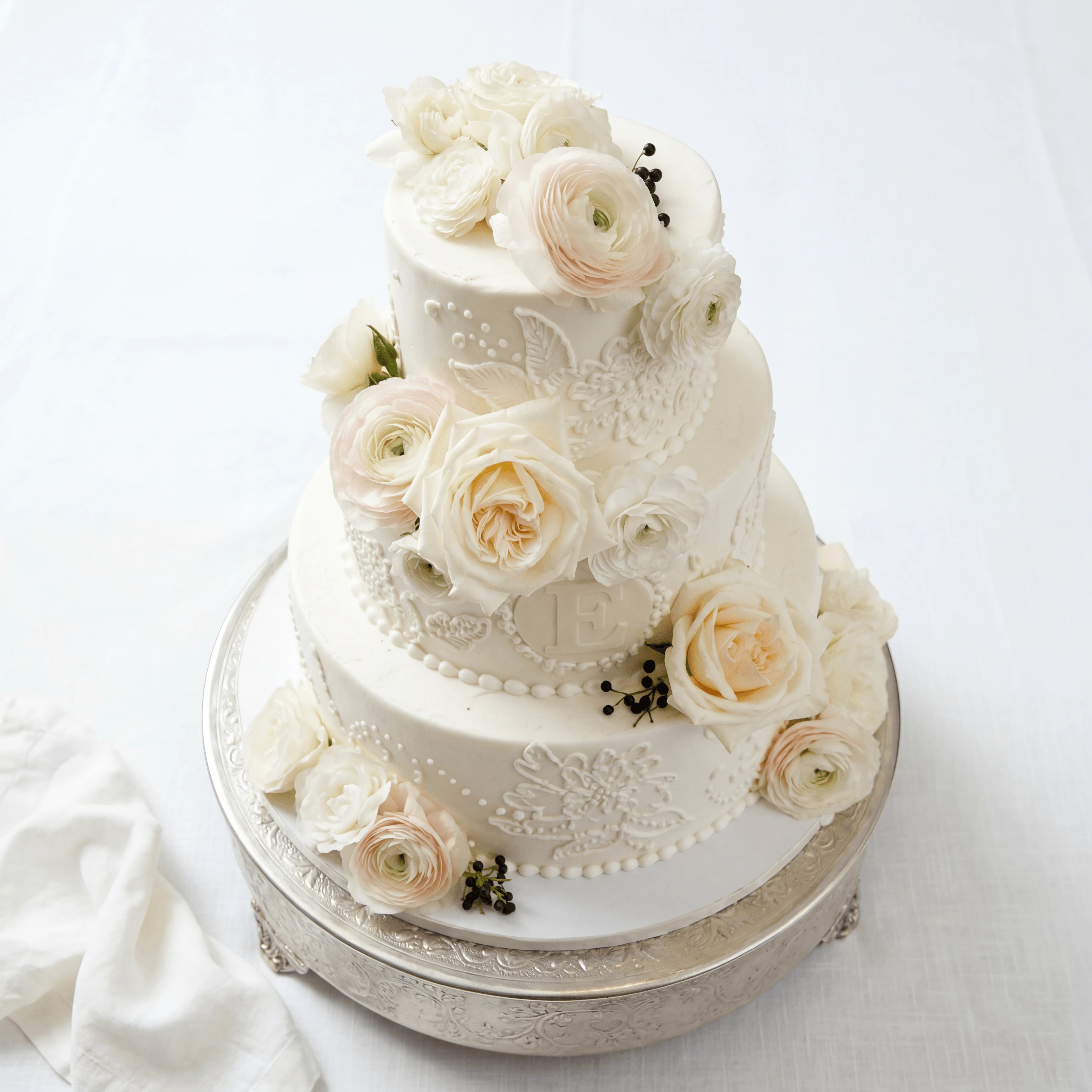 Three-tier round white fondant wedding cake on cake stand — tiered wedding cake photography