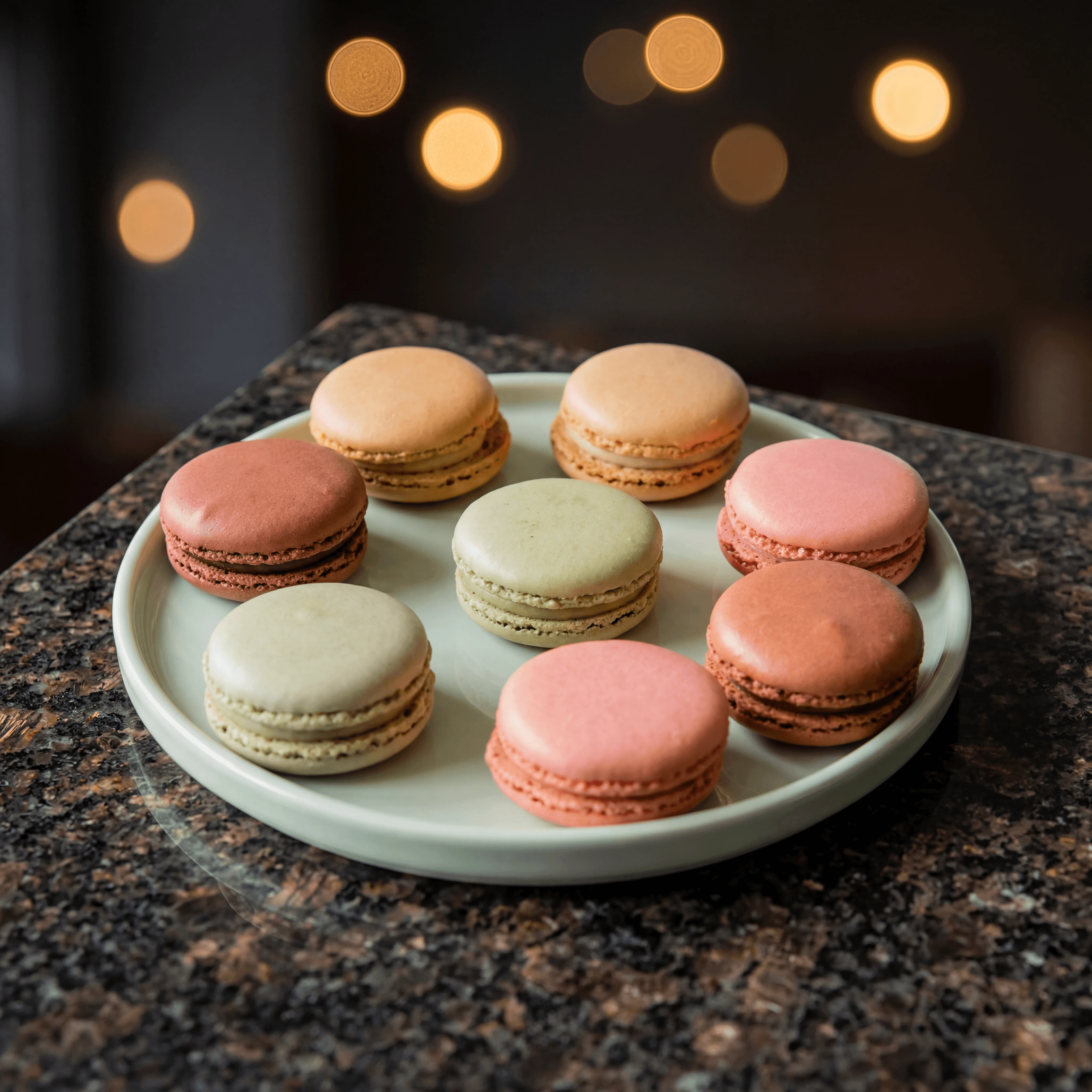 Pastel ombré macaron tower on rose-gold stand with dried rose petals — wedding dessert table photography