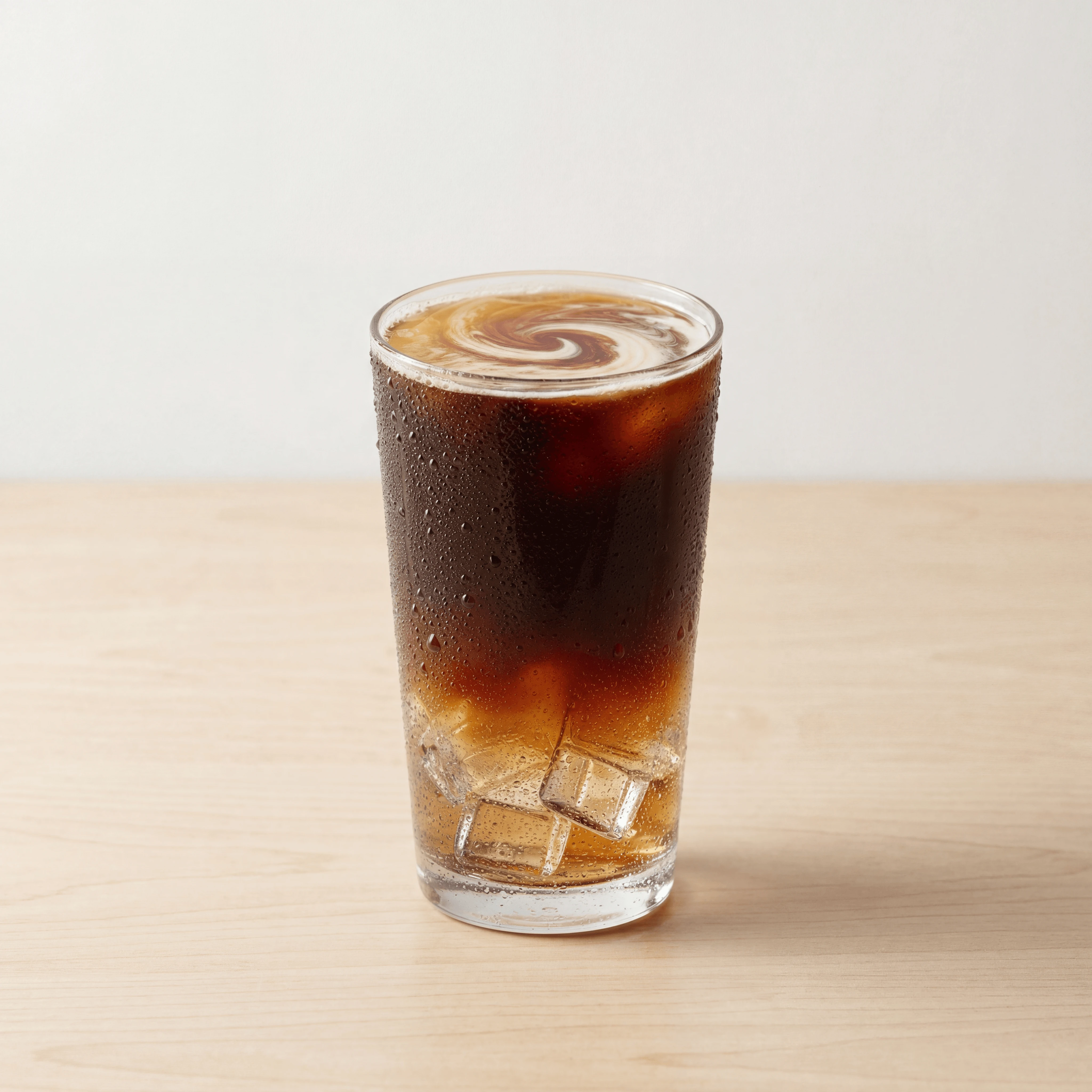 Cold brew coffee tall glass ice cubes condensation light wood — cold brew hero photography