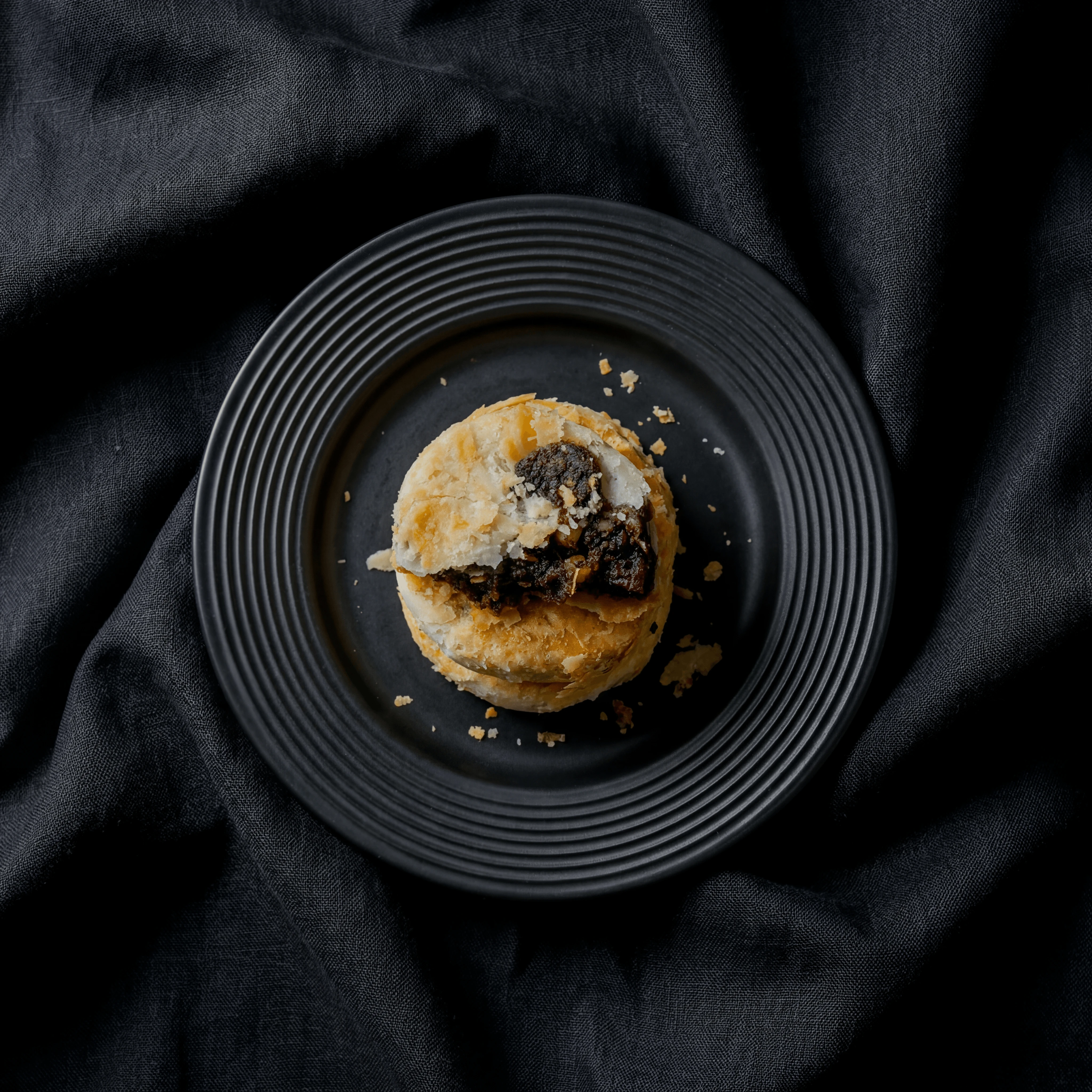 Biscuit din griș umplut cu curmale, secționat, cu praf de zahăr pudră pe drapaj întunecat — fotografie de biscuiți libanezi din Orientul Mijlociu