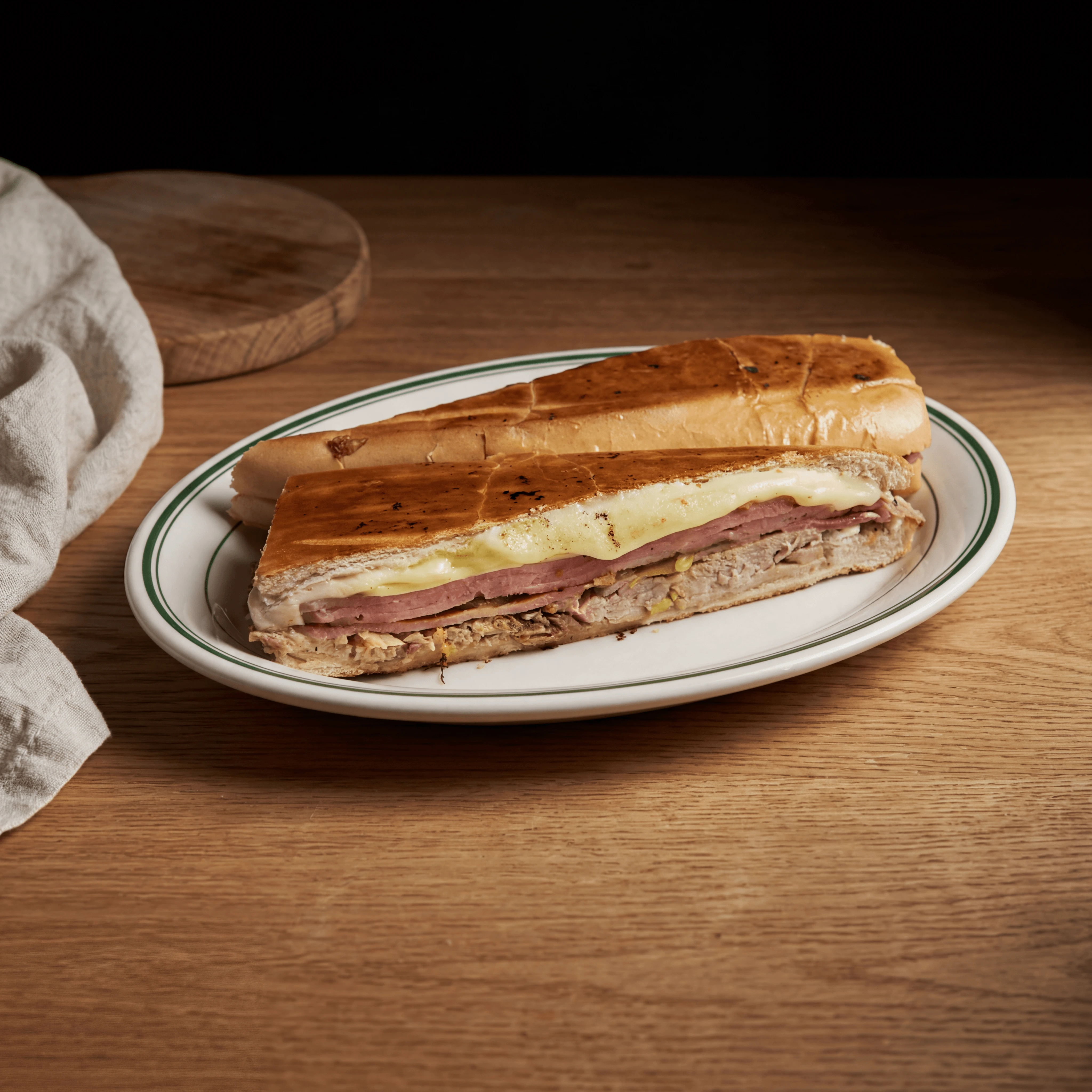 Cuban sandwich cubano cross section ham pork Swiss pickle macro board — iconic cubano FAQ sidebar photography