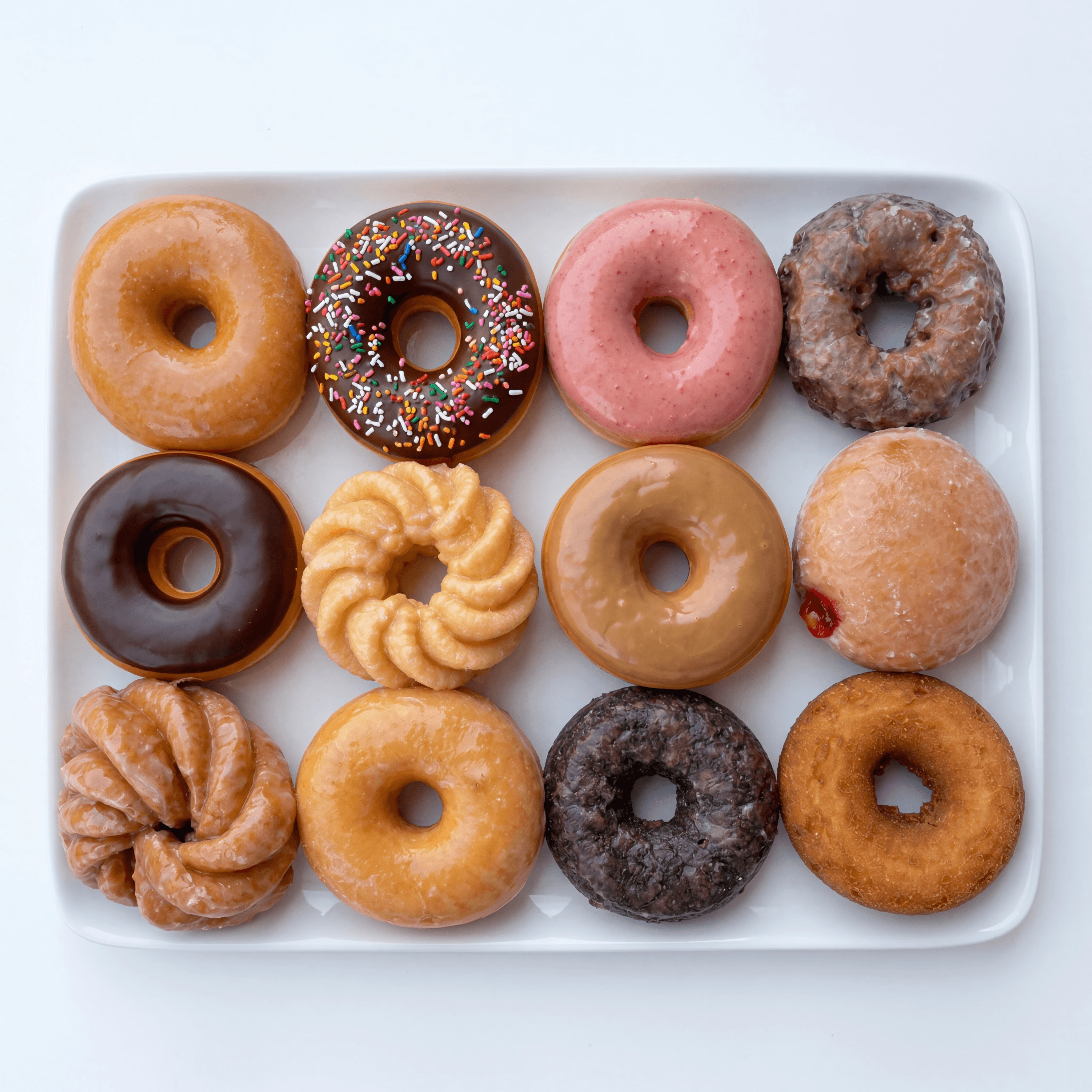 Dozen donuts mixed glazes overhead box white background — boxed dozen hero photography
