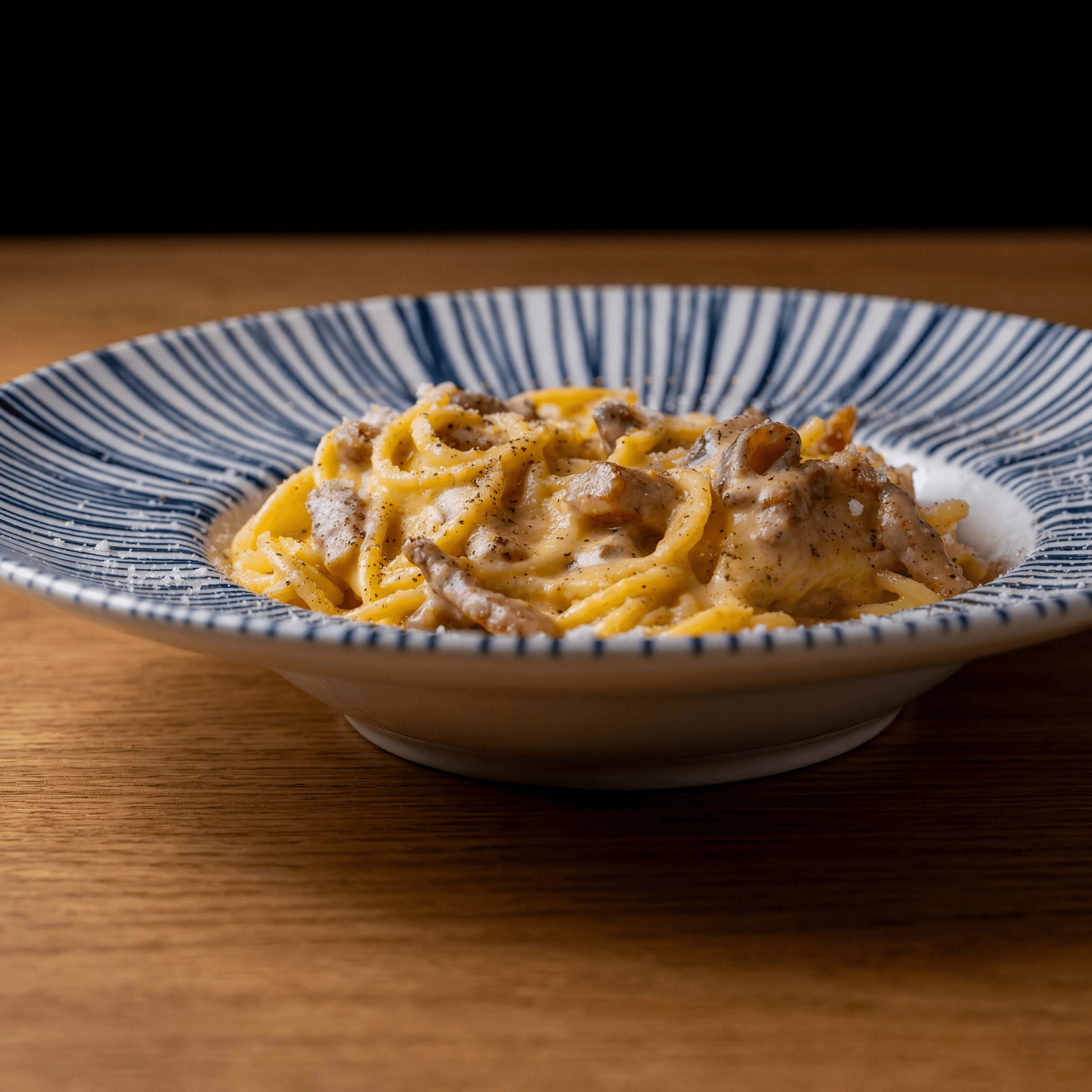 Saffron gramigna pasta with crispy guanciale — Italian portfolio-quality food photography