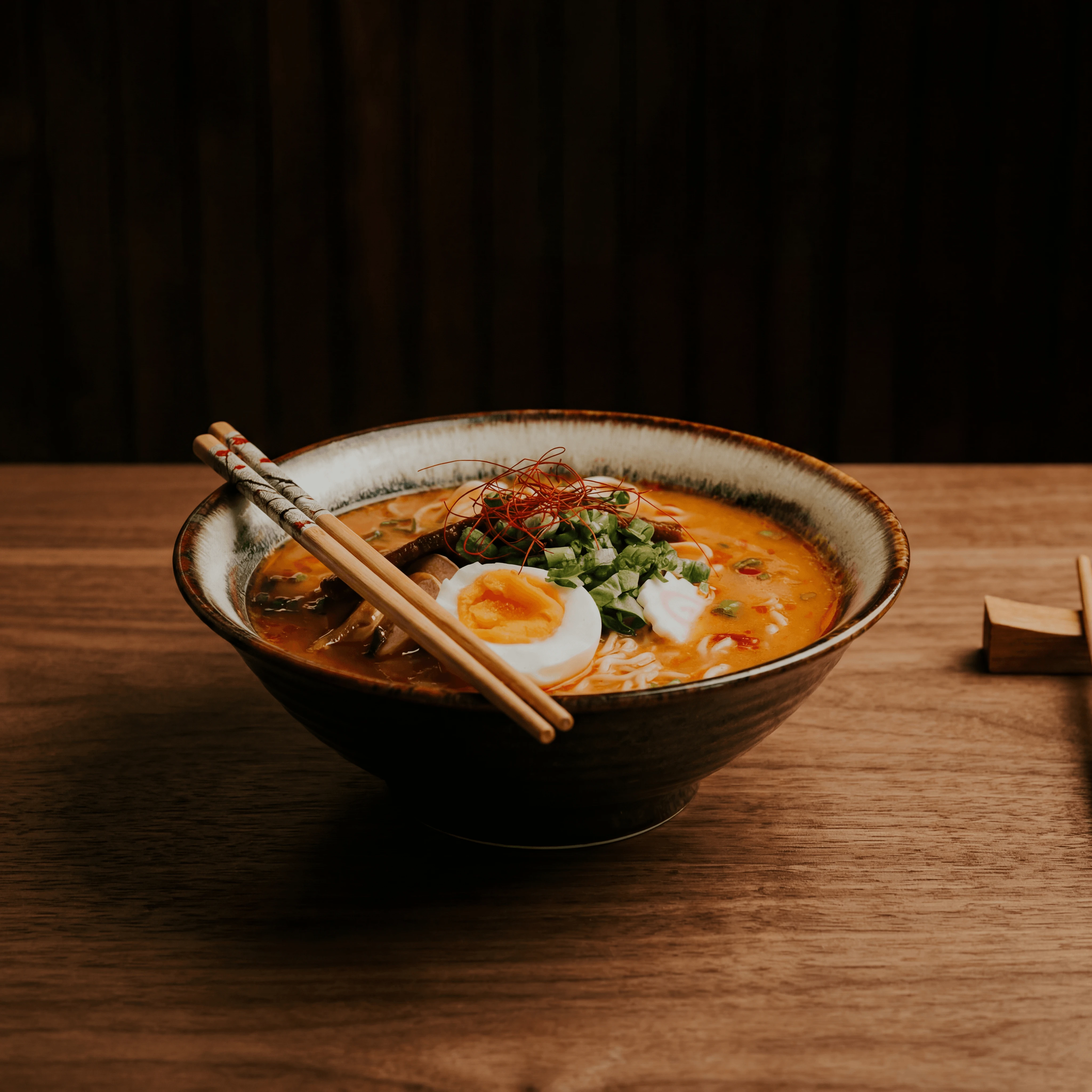 Tonkotsu ramen bowl with soft-boiled egg chashu pork and chili threads — ghost kitchen ramen brand delivery photography