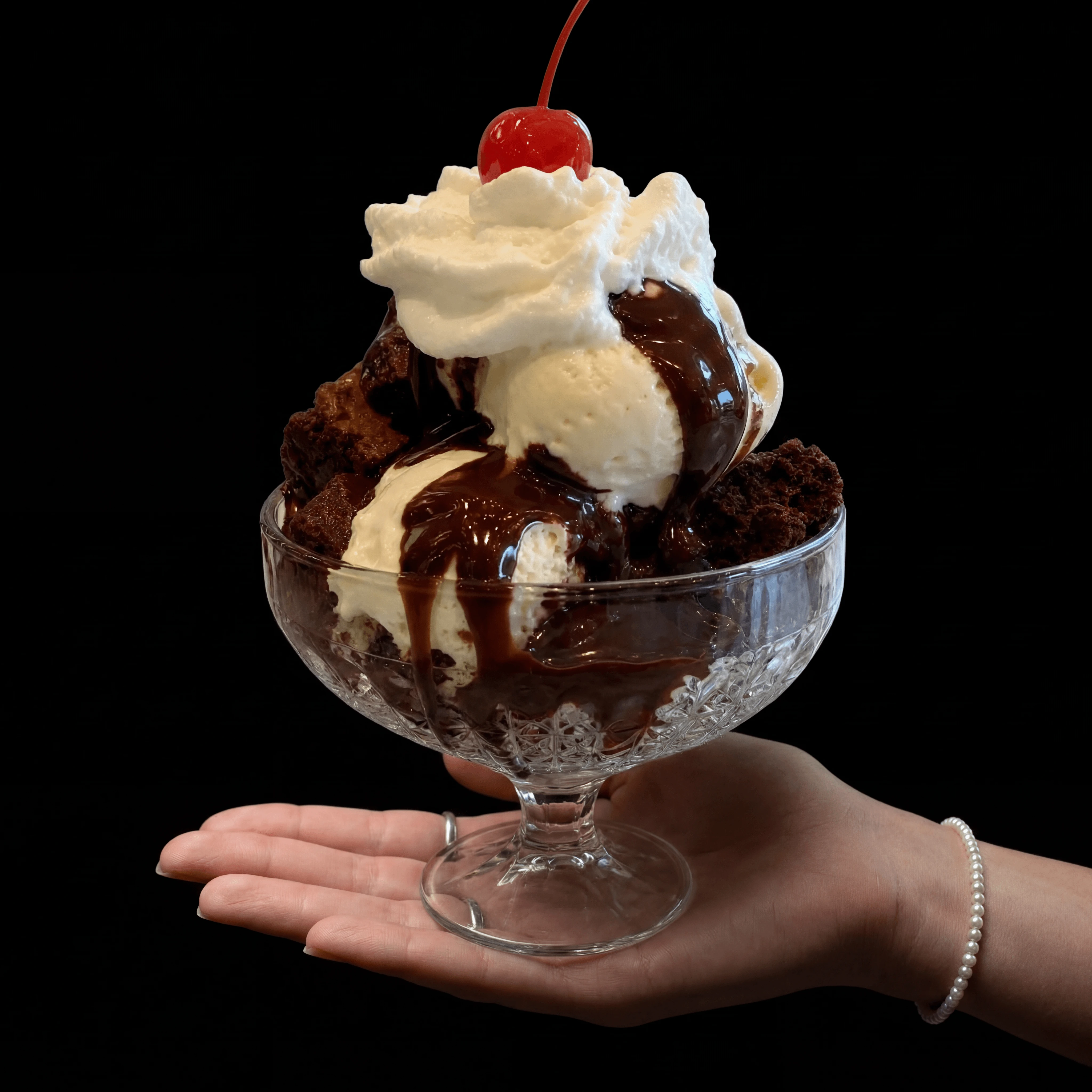 Hot fudge brownie sundae with whipped cream cherry pecans — chocolate cascade scoop shop hero shot