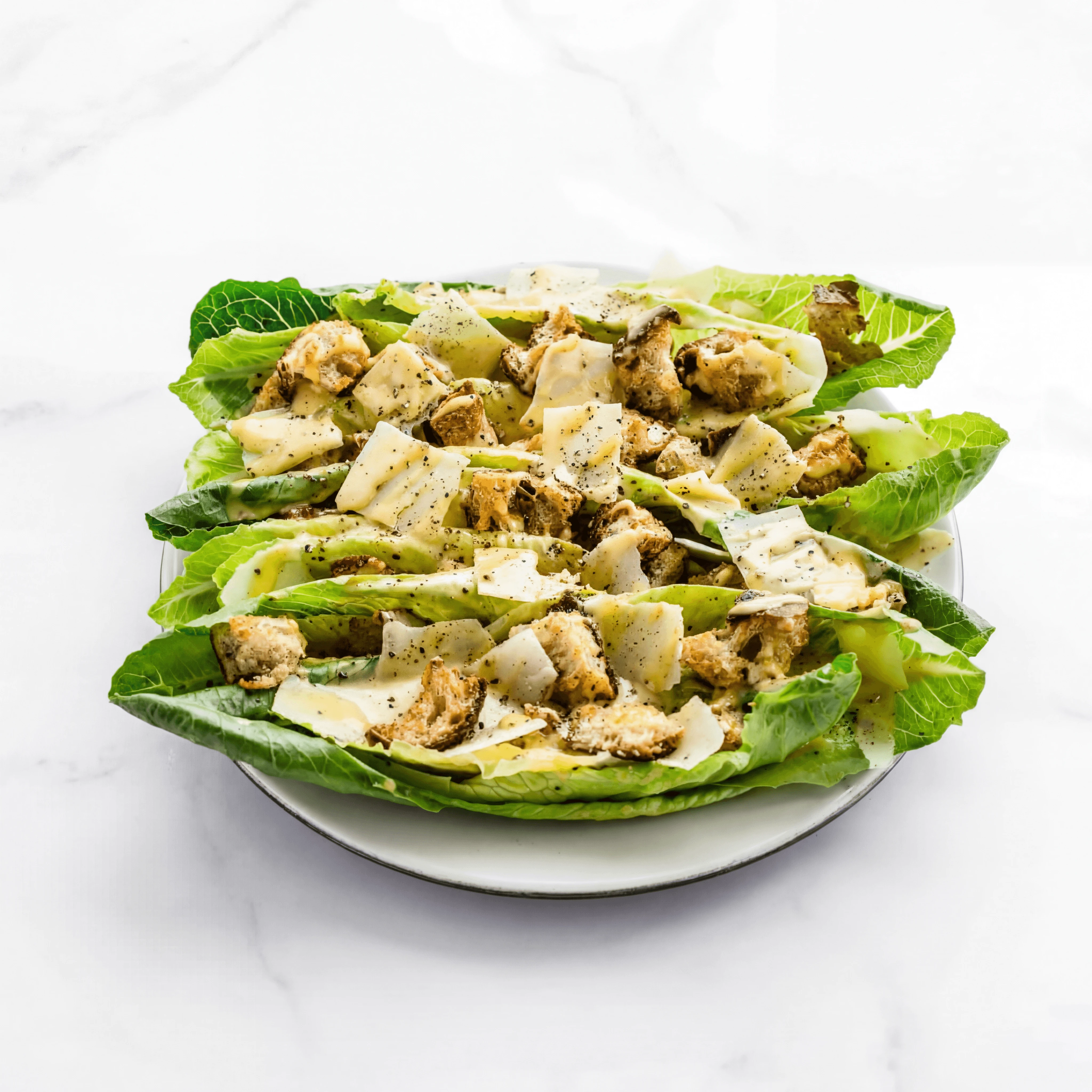 Classic Caesar salad romaine parmesan croutons bright marble — Caesar salad hero photography