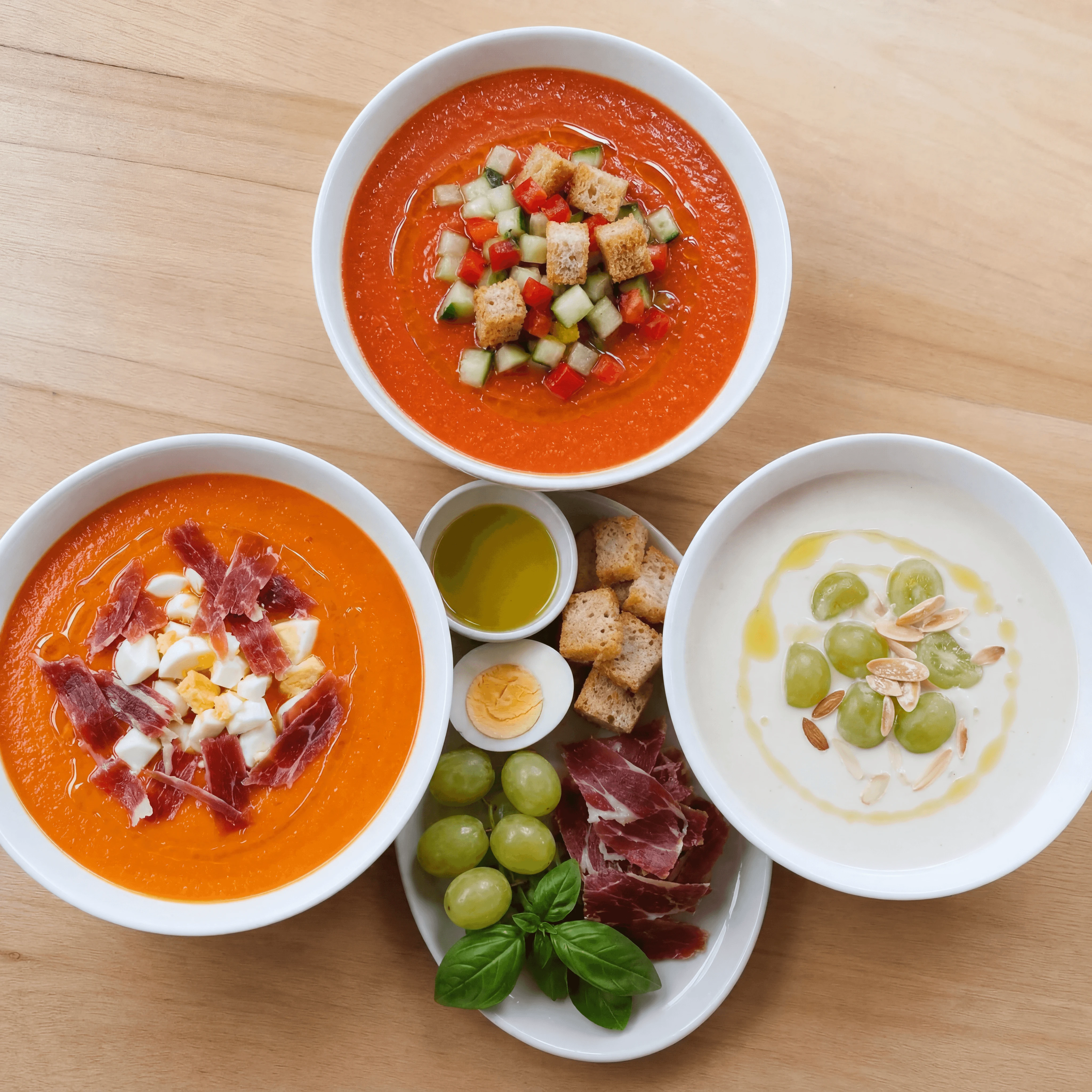 Spanish cold soups gazpacho salmorejo ajoblanco bowls overhead light wood — gazpacho card photography